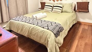 A bedroom with a bed, wooden floor, wall-mounted lights, and a ceiling light.