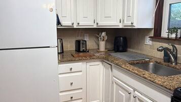 A kitchen with white cabinets, a stainless steel sink, a toaster, and a refrigerator.