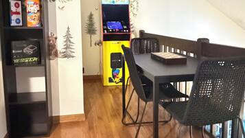A dining area with a wooden table, chairs, and a Pac-Man arcade machine.