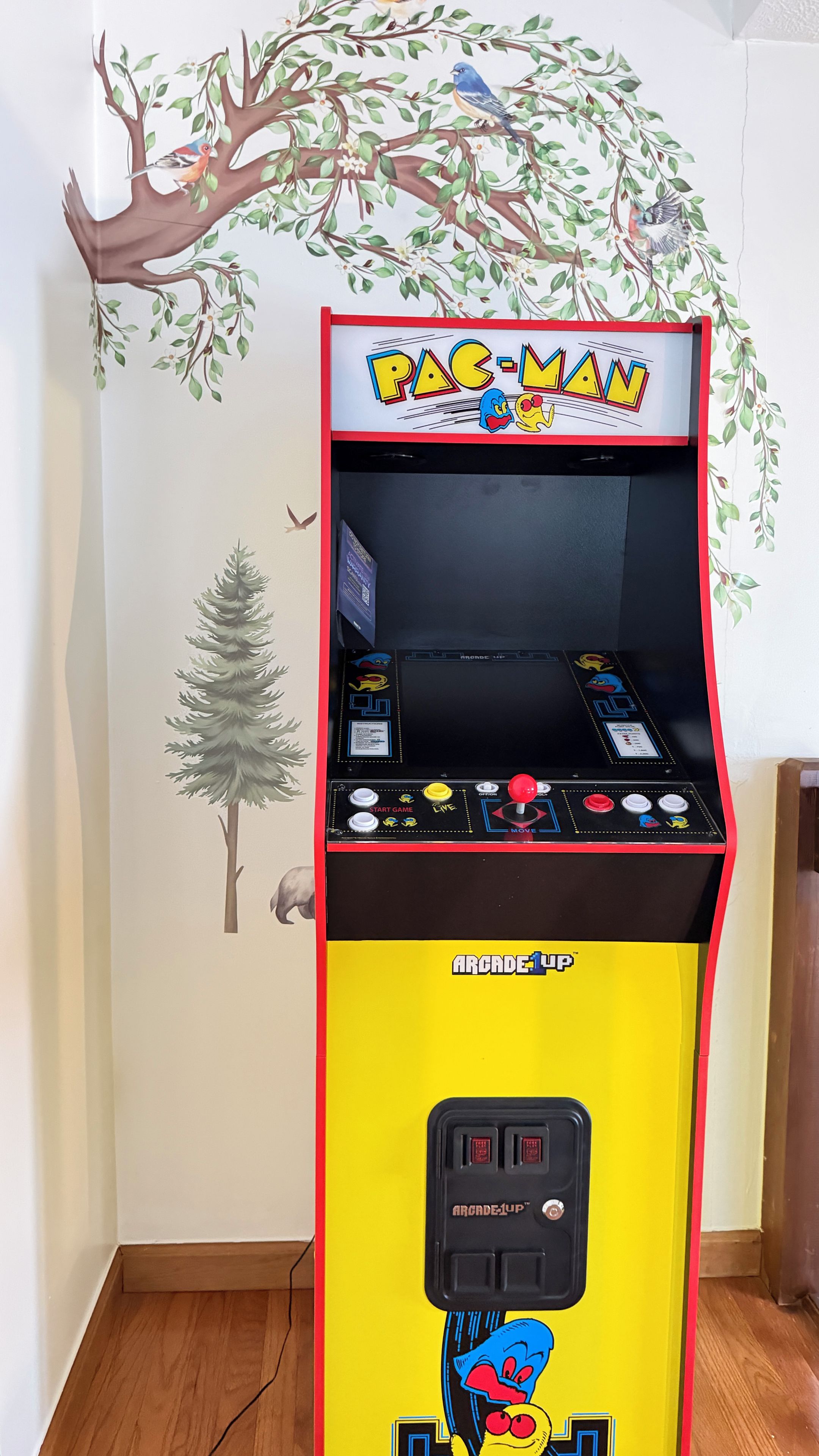 En Pac-Man-spelautomat med en gul och röd färgskala, utrustad med en joystick och knappar på frontpanelen.
