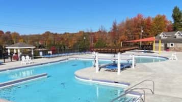 Una piscina con varias pistas, una zona de estar cubierta y un pabellón.