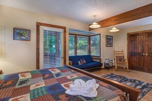 A bedroom with a bed, a bench, a chair, and a view of the outdoors. - Three Little Bears (Gatlinburg)