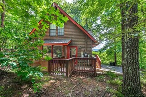 A cabin with a porch, surrounded by trees. - Three Little Bears (Gatlinburg)