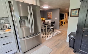 A kitchen with a stainless steel refrigerator, a toaster, and a dining area with a table and chairs.