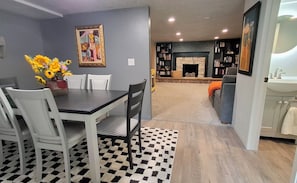 A dining area with a table and chairs, a fireplace, and a bookshelf.
