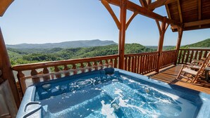 Un bain à remous sur une terrasse en bois, avec vue sur un paysage montagneux.