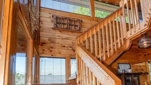 Un escalier en bois menant à un niveau supérieur, d’où l’on peut admirer la vue sur l’extérieur.