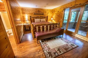 A wooden cabin bedroom with a bed, bench, nightstands, and a rug. - Simply Incredible (Sevierville)
