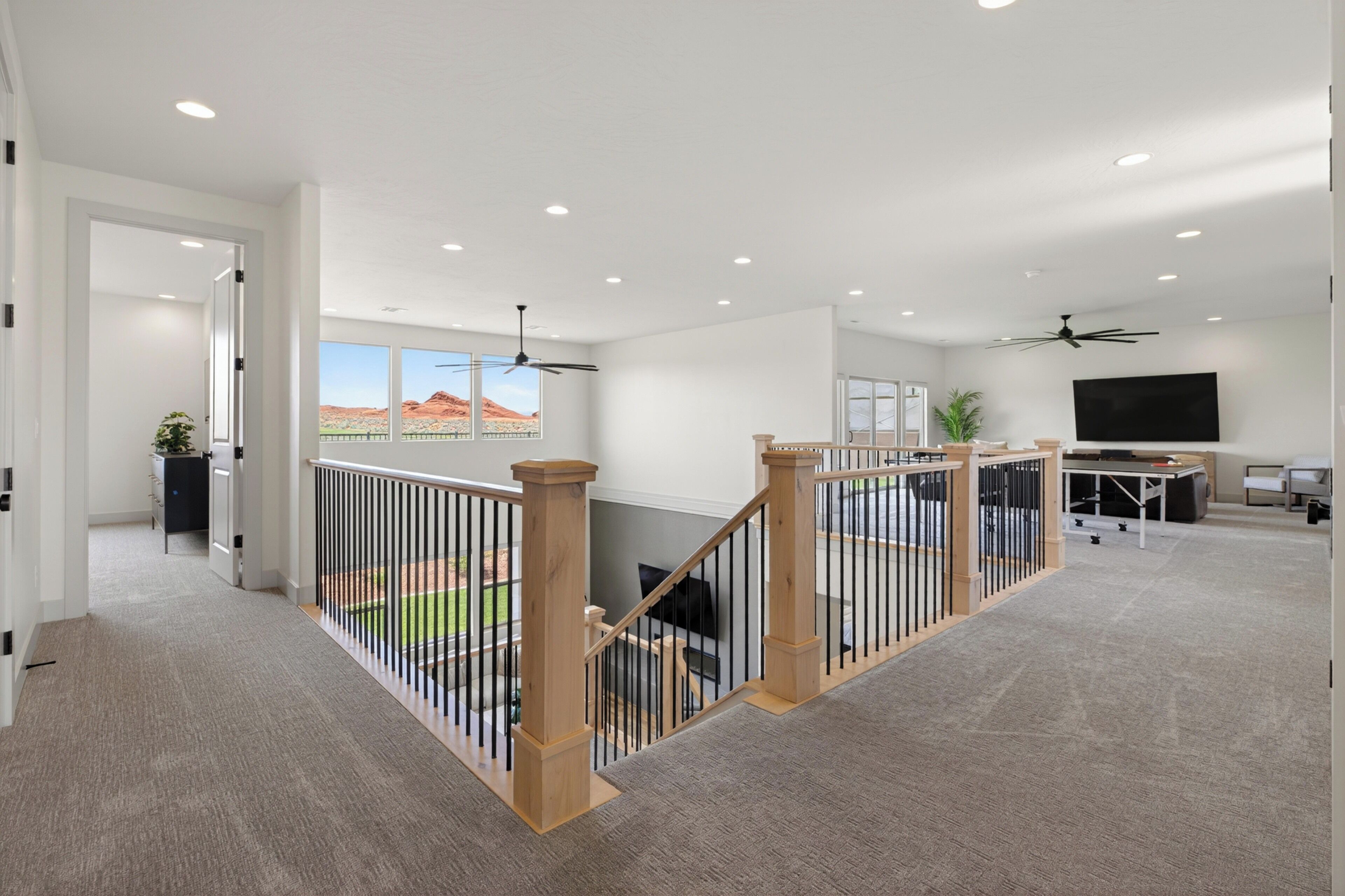 Un intérieur spacieux avec un balcon, des ventilateurs de plafond et un téléviseur à écran plat.