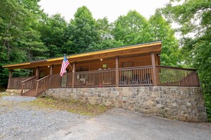 Eine Holzhütte mit Steinfundament, einer Veranda und einer amerikanischen Flagge.