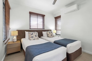 A hotel room with two beds, a nightstand, a lamp, and a ceiling fan. - Bluewater Duo—Lagoon Views & Pool by Trinity Beach (Trinity Beach)