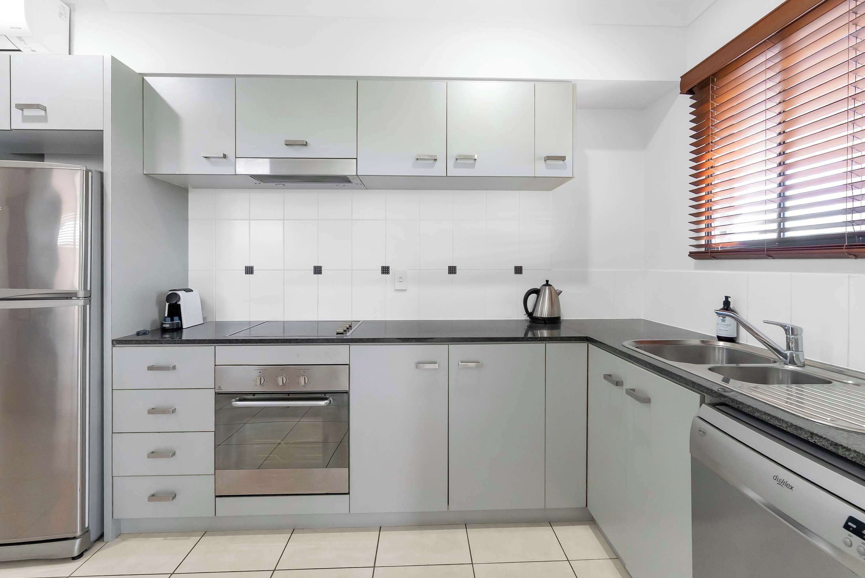 A modern kitchen with stainless steel appliances, white cabinetry, and a built-in oven.