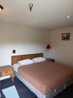 A standard hotel room with a single bed, a nightstand, a lamp, and a painting on the wall.