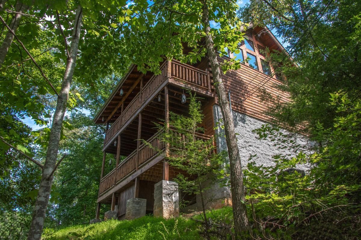 Eine mehrstöckige Holzhütte mit Balkon, umgeben von Bäumen.