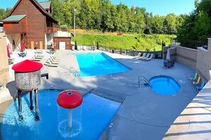 A pool area with a wooden building, lounge chairs, and a small red water feature. - Amazing Grace (Sevierville)