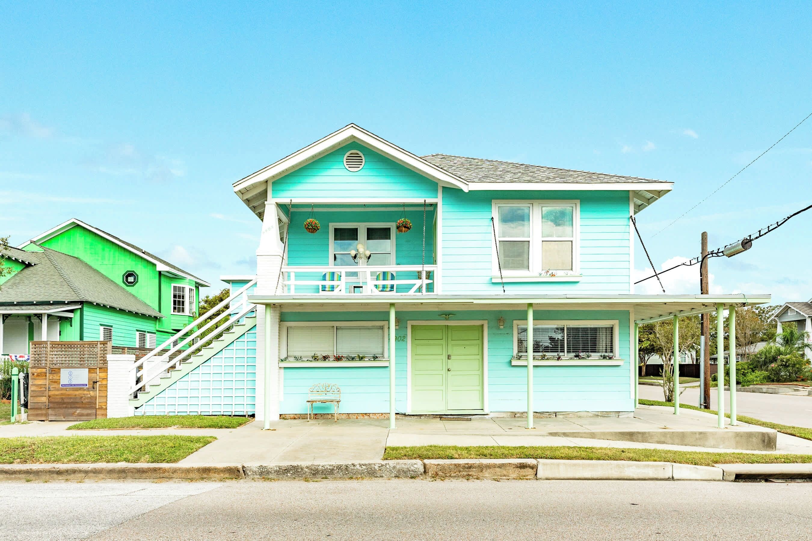 A two-story house with a front porch, a staircase, and a small garden area.