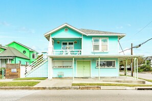A two-story house with a front porch, a staircase, and a small garden area. - Blue Turtle - Vintage Island Charm in Midtown (Galveston)