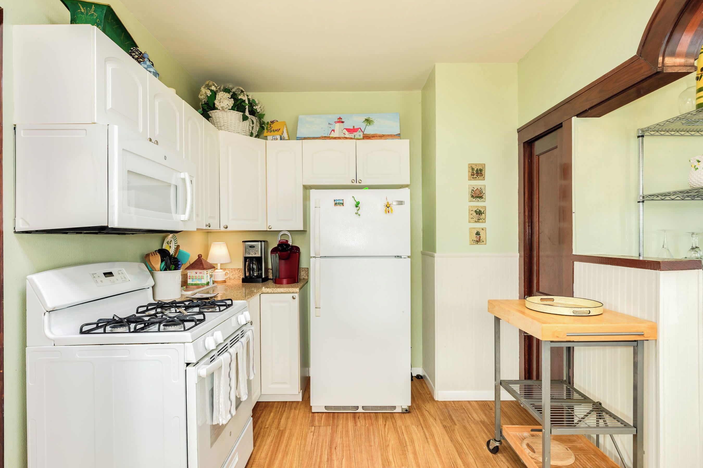 A compact kitchen with white appliances, a gas stove, a microwave, and a refrigerator.