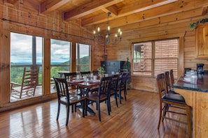 A wooden cabin with a dining area, large windows, and a kitchen. - Splash Mountain (Sevierville)