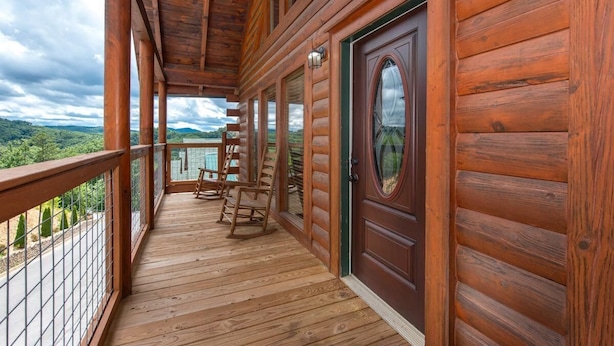 A wooden deck with a view of the landscape, a door, and a lantern. - Splash Mountain (Sevierville)