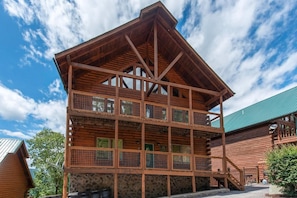 A multi-story log cabin with a stone foundation, wooden balconies, and a green roof. - Splash Mountain (Sevierville)