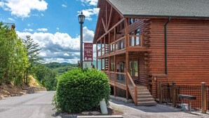 A wooden lodge with a balcony, a sign reading 'Welcome to Black Bear Lodge,' and a view of the surrounding landscape. - Splash Mountain (Sevierville)