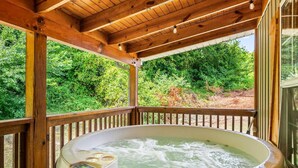 Een hottub op een houten terras, met uitzicht op weelderige begroeiing.
