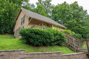 A two-story house with a sloped roof, a front porch, and a wooden staircase leading up to the entrance. - Z - Chalet Morning Pearl (Gatlinburg)