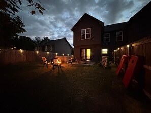 Ein Garten mit Holzzaun, Feuerstelle und Gartenmöbeln.