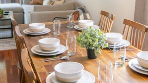 Een eetgedeelte met een houten tafel voor vier personen, omringd door stoelen, met een hanglamp erboven.