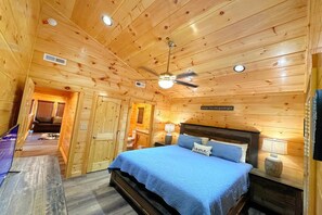 A wooden cabin bedroom with a bed, ceiling fan, and a sign on the wall. - Shepherd's Rest (Pigeon Forge)