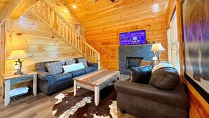A wooden interior with a staircase, a fireplace, a television, and two sofas. - Shepherd's Rest (Pigeon Forge)