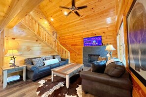 A wooden interior with a staircase, a fireplace, a television, and two sofas. - Shepherd's Rest (Pigeon Forge)