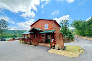 A wooden cabin with a porch, a garage, and a driveway. - Shepherd's Rest (Pigeon Forge)