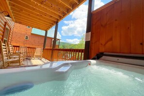 A hot tub area with wooden deck seating and a view of a mountain. - Shepherd's Rest (Pigeon Forge)