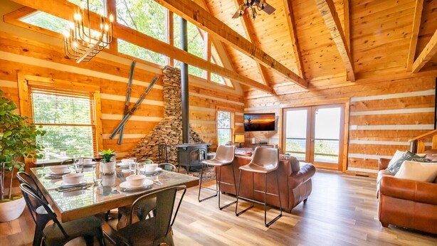 A log cabin interior with a dining area, fireplace, and seating. - Big Bear Lodge at Valley View (Sevierville)