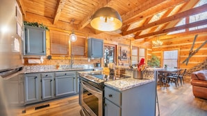 A modern kitchen with granite countertops, stainless steel appliances, and a central island. - Big Bear Lodge at Valley View (Sevierville)