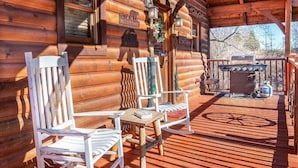 A wooden cabin with a porch, two rocking chairs, a grill, and a welcome sign. - Smokey's Hideaway (Sevierville)