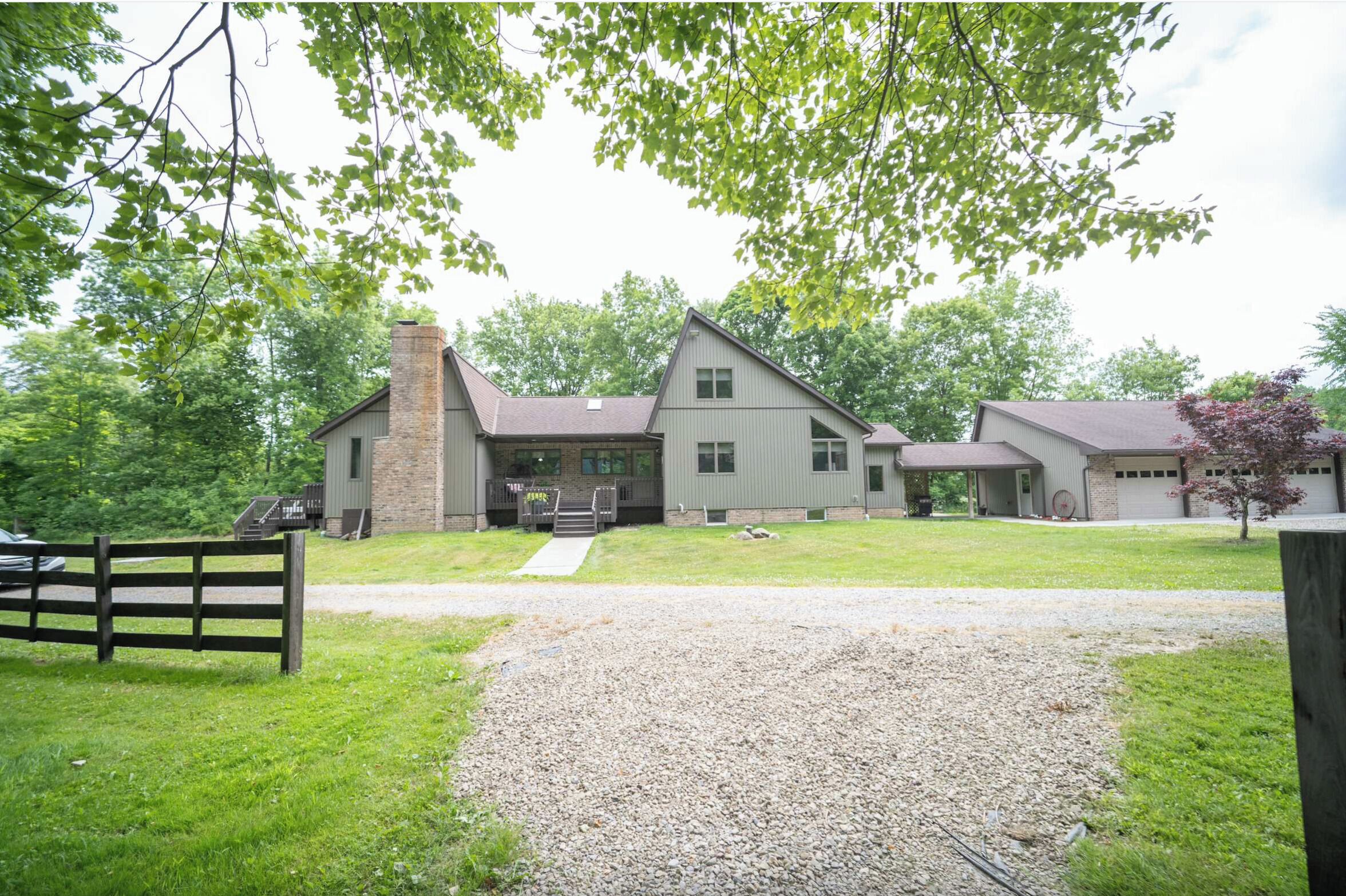 A two-story house with a front porch, a garage, and a gravel driveway.