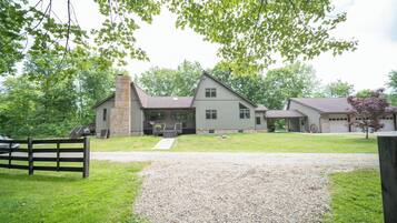 A two-story house with a front porch, a garage, and a gravel driveway.