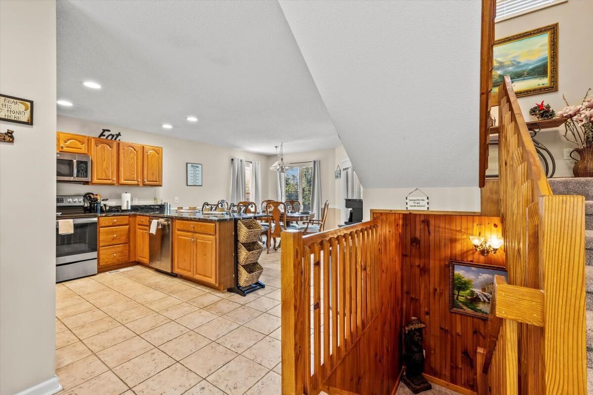 A kitchen with wooden cabinets, a central island, and a dining area with a view.
