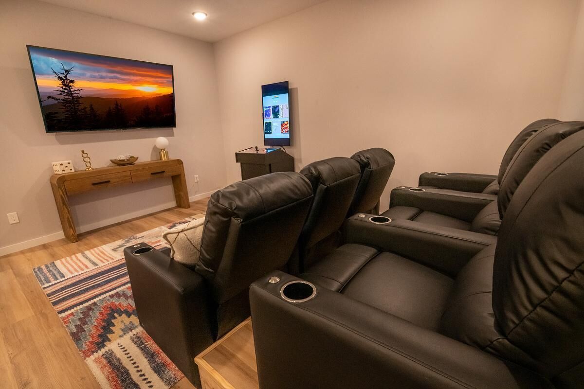Een bioscoopzaal met leren loungestoelen, een flatscreen-televisie en een klein tafeltje met decoratieve objecten.
