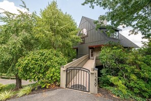 A modern house with a steeply pitched roof, a stone foundation, and a gated entrance. - Window Wonderland (Gatlinburg)