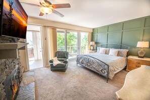 A bedroom with a fireplace, a bed with a headboard, a chair, a nightstand, and a lamp. - Window Wonderland (Gatlinburg)