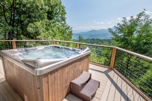 A hot tub on a wooden deck with a view of mountains and trees. - Window Wonderland (Gatlinburg)