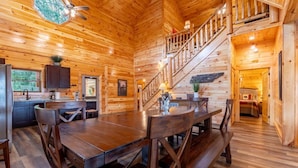 A wooden cabin interior with a dining area, kitchen, and staircase. - Smokey Waters (Sevierville)