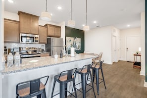 Eine moderne Küche mit Granit-Arbeitsplatten, Edelstahlgeräten und einer Bar mit Barhocker.