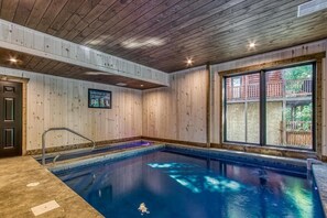 Ein Innenpool mit Holzwänden und Blick auf eine Holzterrasse.