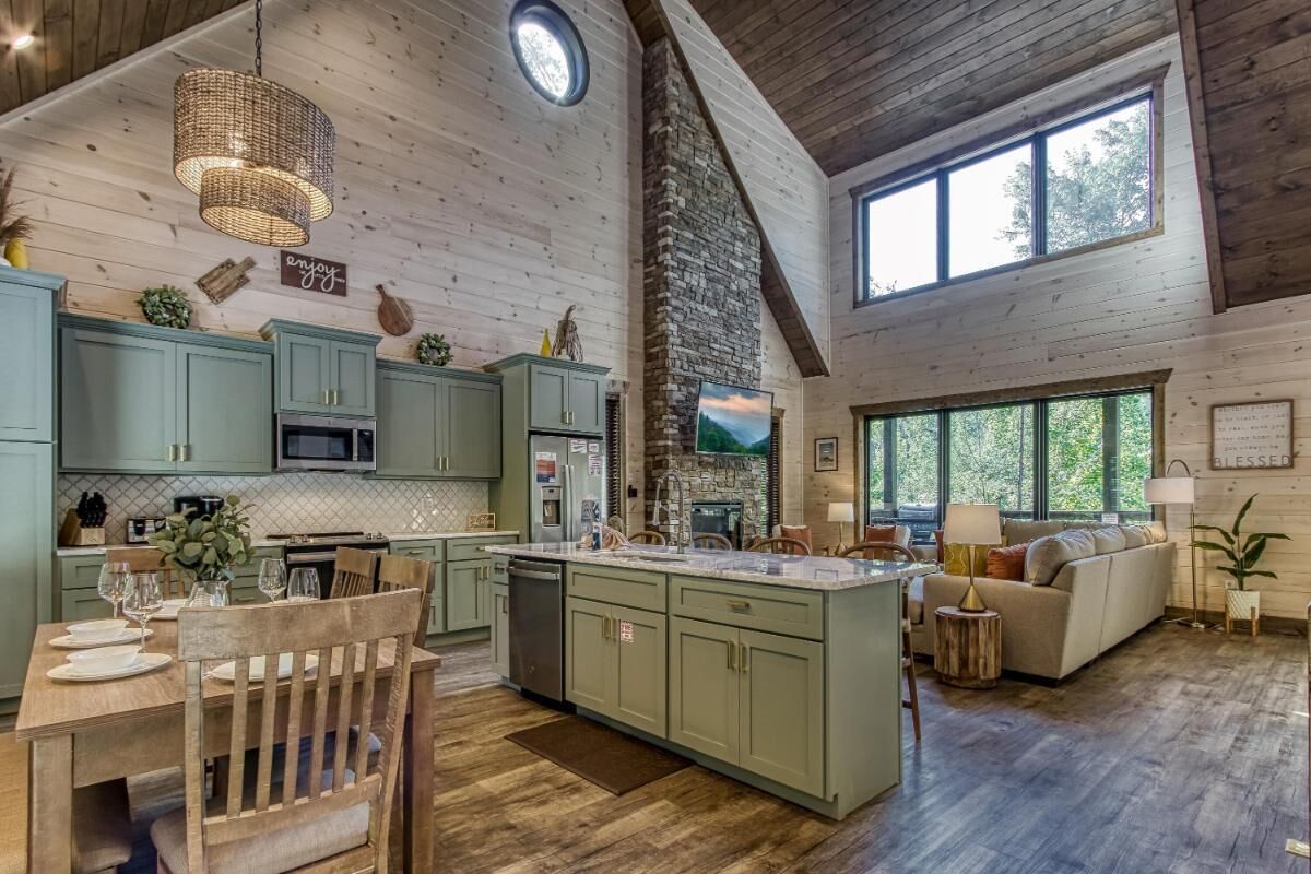 A spacious kitchen with a large island, wooden cabinets, and a stone fireplace.