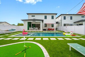 Un pati d'habitatge amb piscina, gespa artificial i zona de terrassa amb mobles d'exterior.